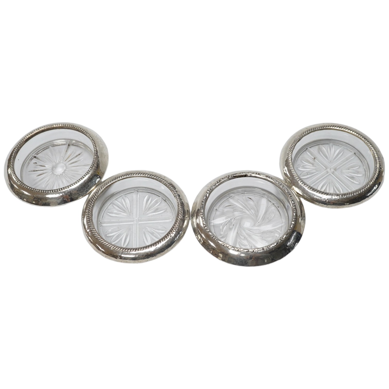 A set of four silver rimmed cut glass coasters, diameter 93mm. Condition - poor